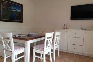 een keuken met een tafel en stoelen en een televisie bij Hochstieg 32, Gonska, Haushälfte in Nieblum
