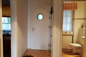 een badkamer met een toilet en een deur met een raam bij Hochstieg 32, Gonska, Haushälfte in Nieblum