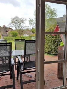 een patio met een tafel en stoelen buiten een raam bij Hochstieg 32, Gonska, Haushälfte in Nieblum +15 foto's