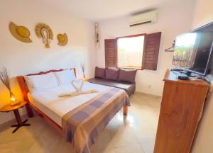 a bedroom with a bed and a tv and a couch at Casa Jeri Guarani in Jericoacoara