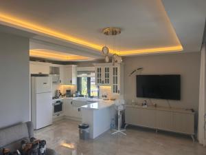 a kitchen with white appliances and a tv on the wall at Villa Ant in Çeşme