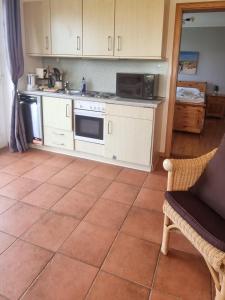 a kitchen with white cabinets and a tile floor at Strandwiese,Haus Faltings Whg 1, EG in Goting