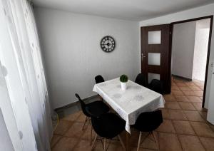 a dining room with a table with chairs and a clock at POMERANIA Pokoje U Oliwii in Rewal +26 photos