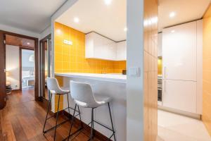 TorreにあるGuestReady - Sunny comfort with a balcony and poolの壁に黄色のタイルが貼られ、スツールが置かれたキッチン