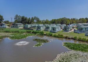 a row of houses and a river with lily pads at Herons Mead Lodges in Orby