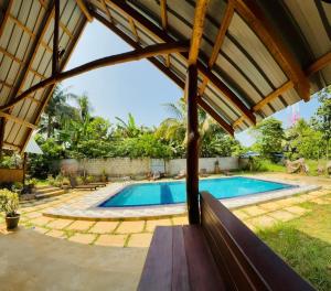 a view of a swimming pool with a wooden pergola at Maika safari lodge in Udawalawe