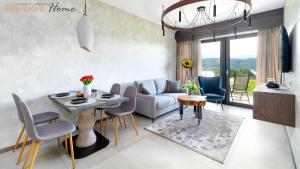 a living room with a couch and a table and chairs at Wonder Hill - bajkowy widok na góry i zalew in Sosnówka