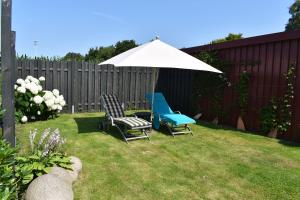 two chairs and an umbrella in a yard at Ferienwohnung Am Moorweg in Ihlow