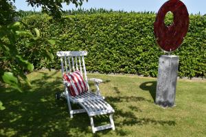 a chair sitting in the grass next to a mirror at Ferienwohnung Am Moorweg in Ihlow
