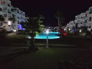 a swimming pool at night with palm trees and buildings at Les jardins de cabo in Cabo Negro