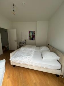 a large white bed in a room with a wooden floor at Berlin -Central-Mitte Light Filled 2BD in Niederdorla +3 photos