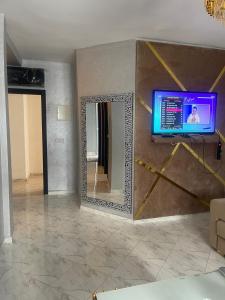 Una habitación con un espejo y un televisor en la pared. en appartement de luxuse, en Alhucemas