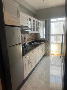 Una cocina con gabinetes blancos y un refrigerador. en appartement de luxuse, en Alhucemas