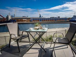 a table and two chairs on a balcony with a train at Hafenspitze App 05 in Wismar