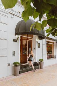 坦迪尔Hotel Francia的一名女子撑着伞走出大楼