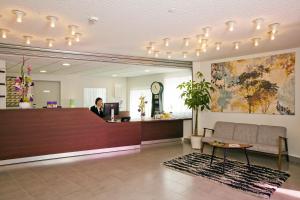 a woman sitting at a reception desk in a lobby at Séjours & Affaires Massy Atlantis in Massy