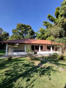ein kleines weißes Haus mit einem roten Dach in der Unterkunft Casa de Campo com Lago e Jardim - Pet-Friendly in Miguel Pereira