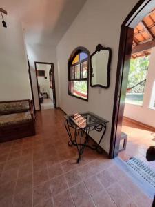 ein Wohnzimmer mit einem Tisch und einem Spiegel in der Unterkunft Casa de Campo com Lago e Jardim - Pet-Friendly in Miguel Pereira + 12 Fotos