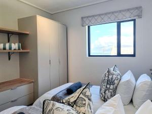 a bedroom with a bed with pillows and a window at Wavescapes Hang Ten Stay in Cape Town