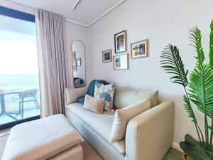 a living room with a couch and a window at Wavescapes Tides Stay in Muizenberg