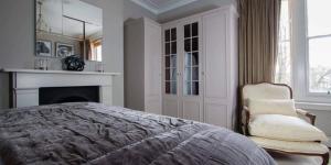 a bedroom with a bed and a chair and a fireplace at Super Chic 1-Bedroom Urban Hideaway in Twickenham