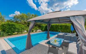 una piscina con sombrilla junto a una piscina en Villa FourM - Makarska by Villas Guide, en Poljica