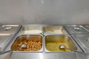 a metal tray with four trays of food with spoons at FlexiBay-Affordable Hostel in North Delhi in Delhi