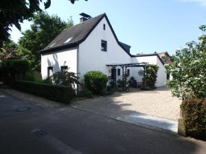 a white house with a black roof and a driveway at Ferienwohnung Knusperhaus in Xanten