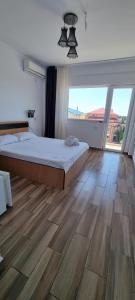 a bedroom with a large bed and a large window at Blue Sky Hotel in Eforie Nord