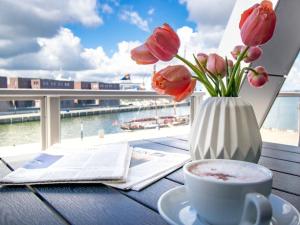 una mesa con un jarrón de flores y una taza de café en Hafenspitze App 23, en Wismar