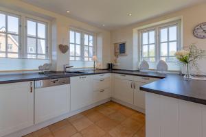 a kitchen with white cabinets and black counter tops at Stine Marie 1 in Borgsum