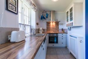Una cocina con gabinetes blancos y una encimera de madera. en Haus Lotte, en Utersum