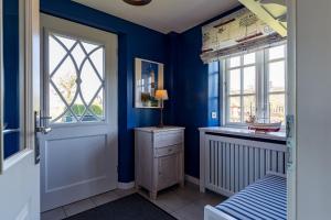 1 dormitorio con paredes azules, 1 cama y ventana en Haus Lotte, en Utersum