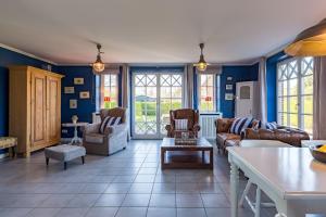 Una sala de estar con paredes azules y muebles de cuero. en Haus Lotte, en Utersum