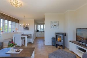 a living room with a fireplace and a dining room at Stine Marie 2 in Borgsum