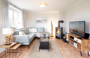 a living room with a couch and a tv at Haus Grünland in Alkersum