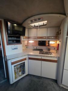 Una cocina para vehículos recreativos con estufa y microondas. en Freedom boat house, en Faro