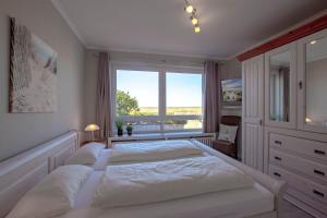 a white bedroom with a large bed and a window at Haus am Strand in Wyk auf Föhr