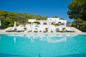 a swimming pool with chairs and a villa in the background at Stunning Modern Ibiza Villa with Private Pool,1252 in Cala Vadella