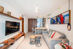 a living room with a couch and a table at Apto Porto Smeralda Guarajuba c/ varanda - PSMC003 in Camacari