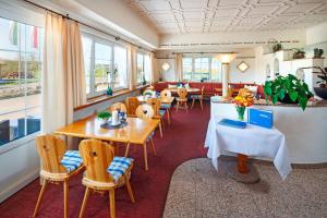 a restaurant with tables and chairs and windows at Seemöwe Wellnesshotel Swiss Quality in Güttingen