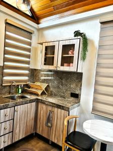 eine Küche mit Holzschränken, einer Spüle und einem Tisch in der Unterkunft Granny's Woods Cottage in Ranau