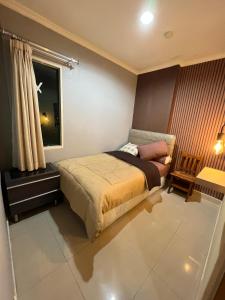 a bedroom with a bed and a table and a window at Spacious living room Hampton's Park Apartment in Jakarta