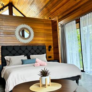 a bedroom with a large bed with a mirror on the wall at Granny's Woods Cottage in Ranau
