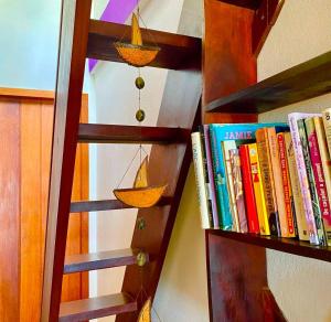 a wooden book shelf filled with books next to a wall at Casa Sol Nascente in Itacaré
