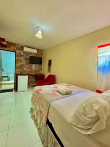 een slaapkamer met een groot bed en een rode stoel bij Pousada Meu Xodó in São Miguel dos Milagres +13 foto's