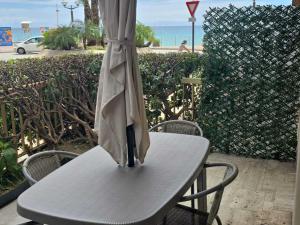 un parapluie posé sur une table blanche dans l'établissement Studio RDJ avec terrasse, bord de mer, WIFI, animaux acceptés - FR-1-196-367, à Roquebrune-Cap-Martin 7 autres photos