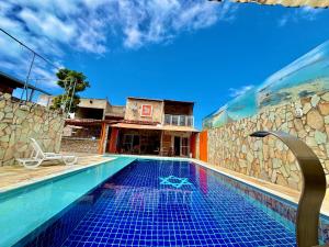 een zwembad bij een huis met een stenen muur bij Pousada Meu Xodó in São Miguel dos Milagres