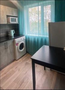 een keuken met een wasmachine en een tafel bij Абая 35 1 in Temirtaū