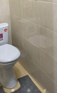 een badkamer met een toilet en een betegelde muur bij Абая 35 1 in Temirtaū